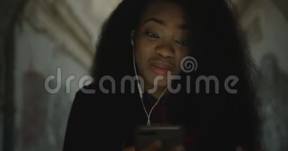 肖像年轻美丽快乐的非洲女孩微笑阅读短信移动户外4k一个单独的情感视频的预览图