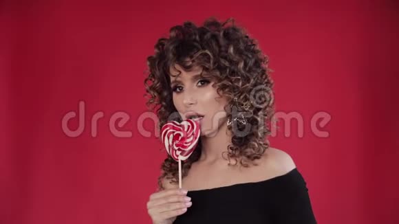 年轻漂亮的女孩拿着美味的棒棒糖吃它视频的预览图