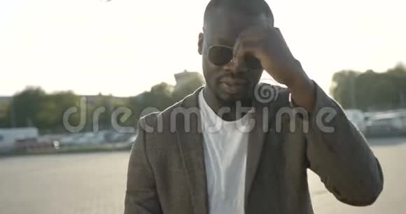 一位时尚严肃的美国黑人男子的特写肖像戴着太阳镜在向前走时摸着头发视频的预览图