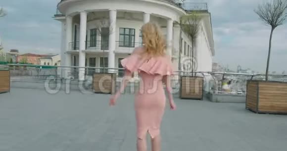 迷人的幸福女人金发和自然化妆粉红色的裙子正在享受天气她在旋转视频的预览图