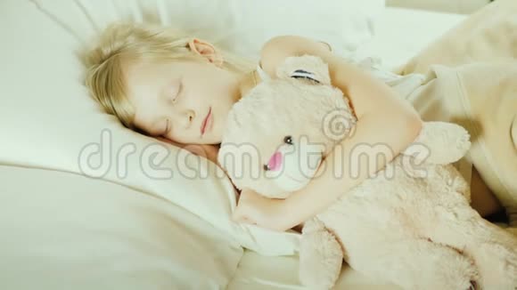 俯视图小女孩和她的宠物玩具睡在床上视频的预览图