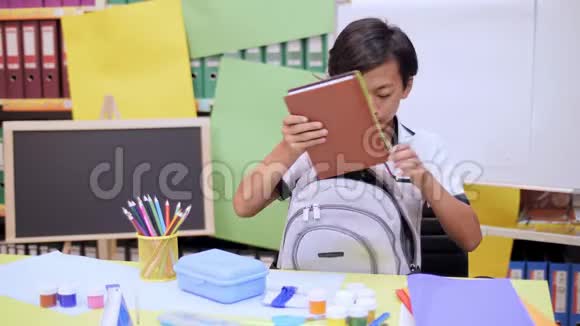 男孩把课本和笔记本叠成一个书包视频的预览图