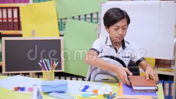 男孩把课本和笔记本叠成一个书包视频的预览图