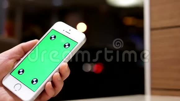 女人拿着绿色屏幕手机美丽的模糊灯光背景视频的预览图