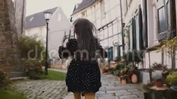镜头跟随小女孩在铺好的道路上奔跑后景德国哈廷根的古代半木房4K视频的预览图