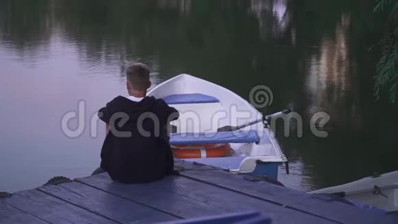 帅哥坐在船边的码头上视频的预览图