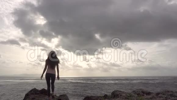 乔格女士举起双手站在靠近海洋的岩石上视频的预览图