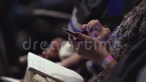 带记事本的女孩坐在会议室滚动屏幕库存特写的女性手正在输入短信视频的预览图