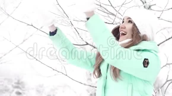 年轻的女人玩雪慢慢地把它扔起来视频的预览图