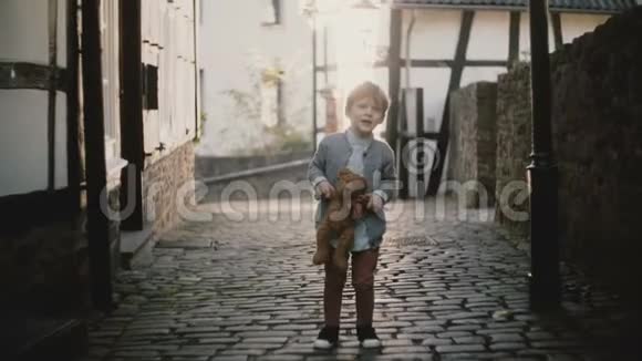 可爱的欧洲男孩在街上唱歌男孩子抱着一只玩具熊天赋表达旧铺镇路4K视频的预览图