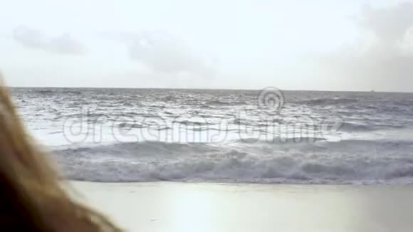 女人举手欣赏海滩海景视频的预览图