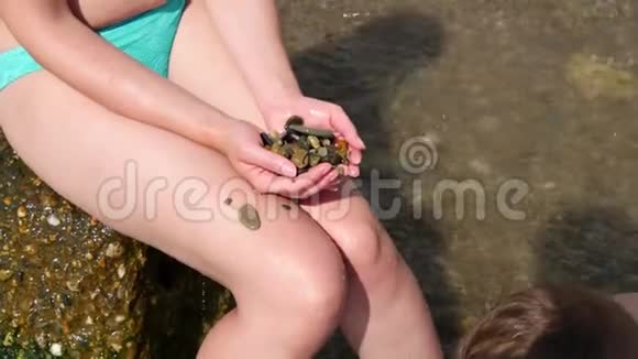 孩子用自己的手把鹅卵石交到妈妈手里然后把它们带回鹅卵石滩视频的预览图