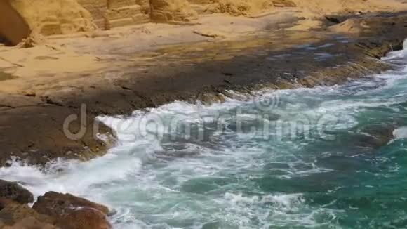 在岩石海岸附近有白色泡沫的绿色海浪缓慢运动视频的预览图