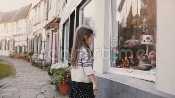 两个小朋友站着看着一个玩具商店的橱窗欧洲儿童在店面附近交谈半木房4K视频的预览图