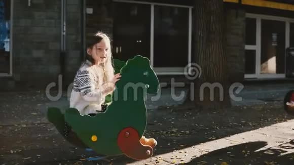 一个骑着绿色恐龙春游的漂亮女孩快乐的白人孩子兴奋和父母交谈阳光明媚4K视频的预览图