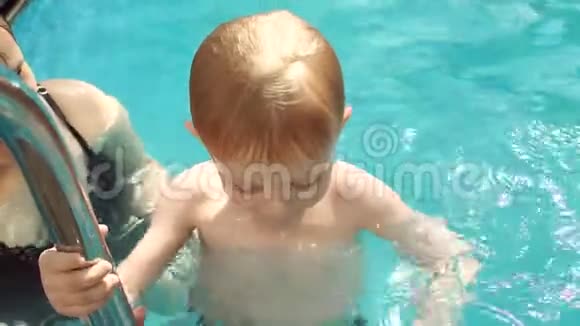 特写快乐妈妈教儿子在游泳池里游泳暑假视频的预览图