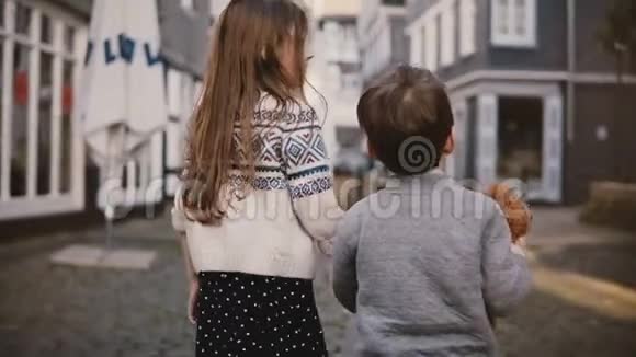 镜头跟随小女孩和男孩一起走后景两个孩子在老城闲逛兄弟姐妹4K视频的预览图