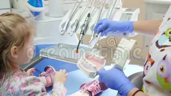 口腔科医生为儿童在牙椅上展示工具并在模型颌骨特写上教授刷牙视频的预览图