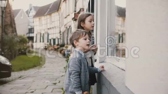 女孩和男孩指着玩具商店橱窗里的礼物两个欧洲孩子在商店里许愿一半的木屋4K视频的预览图