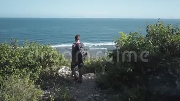 从上面看到旅行背包客欣赏悬崖上的海景视频的预览图