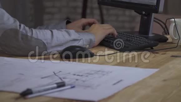 那个人坐在桌子旁在键盘上打字旁边是图纸视频的预览图