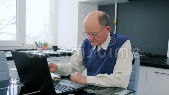 退休老人在家工作爷爷坐在网上购物手提电脑手里拿着文件视频的预览图