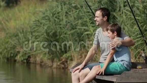 微笑的男孩和他的父亲在码头钓鱼视频的预览图