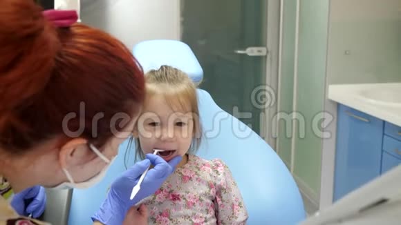 带特殊器械的女医生在牙科扶手椅中治疗漂亮孩子的牙齿视频的预览图