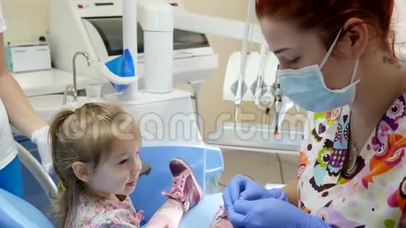 可爱的女孩坐着看医生戴着医用口罩和手套为诊所的手术准备特殊的工具视频的预览图