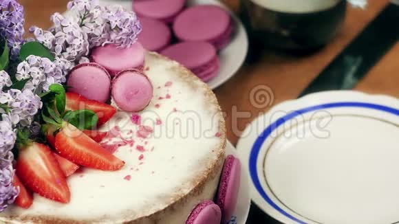 女人的手切下一块蛋糕上面装饰着玛卡龙草莓和丁香花4K慢悠悠视频的预览图