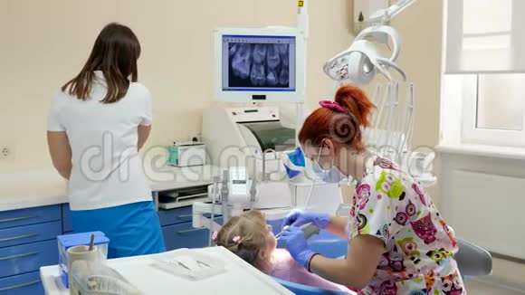 医生给戴医药口罩的妇女在医院的轮椅上给孩子治疗牙齿视频的预览图