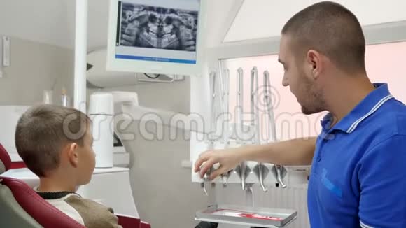 英俊的医生与病人交谈展示牙科治疗工具视频的预览图
