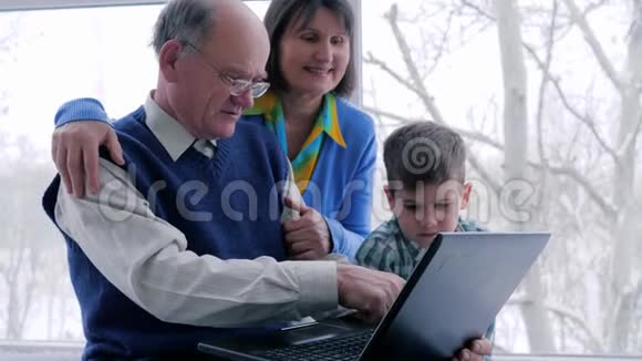 网上购物家庭休闲奶奶和爷爷带着孙子坐在网上通过笔记本电脑视频的预览图