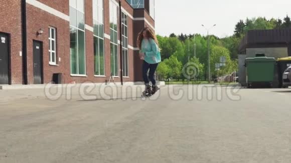 在城市的柏油路上骑着溜冰鞋的快乐少女视频的预览图