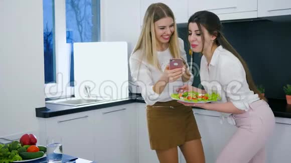 在室内吃早餐时笑着朋友在智能手机上看有趣的照片视频的预览图