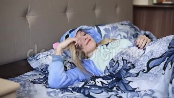 早上穿着蓝色睡衣躺在床上的金发女孩视频的预览图