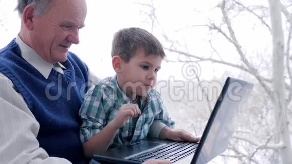 家庭教育有祖父的孩子在室内通过笔记本电脑上网视频的预览图