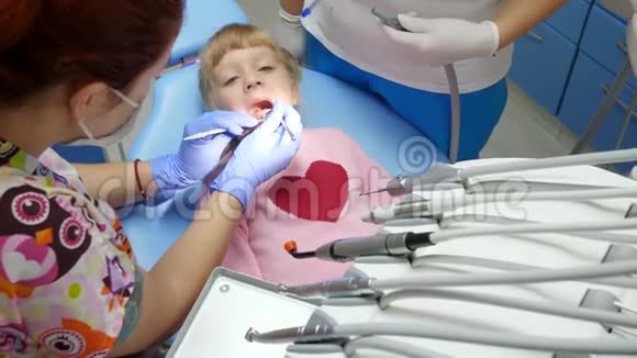小病人张开口的拇指躺在牙科椅上由专家用武器治疗视频的预览图
