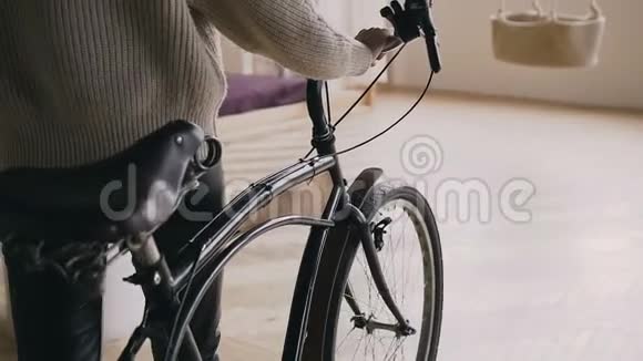 一个女孩躺在室内老式固定齿轮自行车的车把上的裁剪特写镜头后视视频的预览图