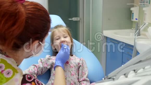 医学和医疗保健女医生戴着带特殊工具的橡胶手套治疗快乐的小女孩的牙齿视频的预览图