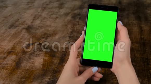 女子手持黑色智能手机与空白绿色屏幕模拟概念视频的预览图