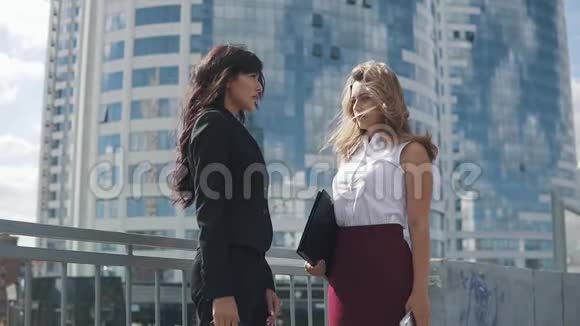 在现代建筑背景下谈生意的女人两个穿正式西装的年轻迷人的女人视频的预览图