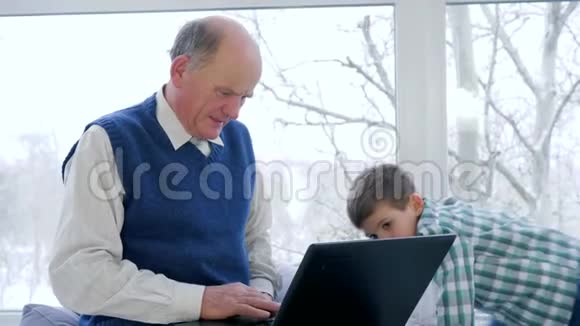 养老金领取者的网络交流祖父与孙子挥舞手提电脑互相拥抱在家里视频的预览图