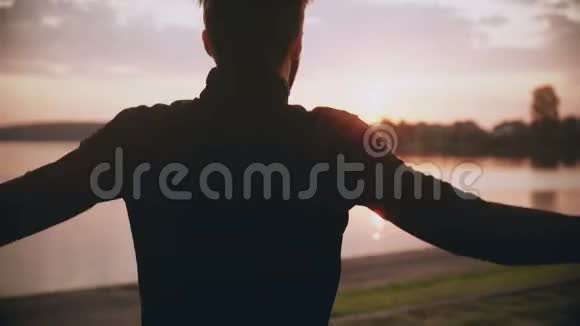 4K运动员在日出的早晨湖边锻炼后视男性摆动手臂和跳跃职业健康运动员视频的预览图