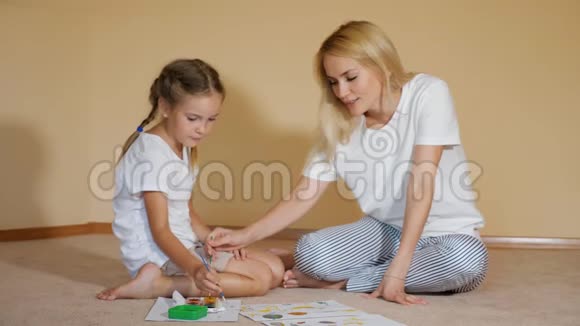 女孩们坐在地板上一边拿着纸和水彩一边互相画鼻子玩得很开心视频的预览图