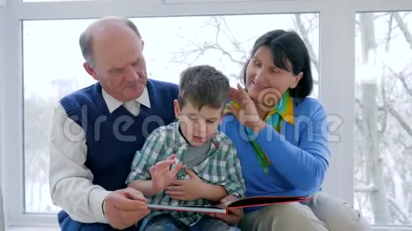 手里拿着书的小男孩在度假时和爷爷奶奶一起读书视频的预览图
