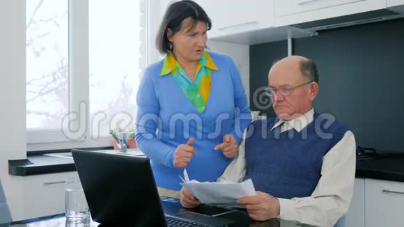 支付在线养老金的人家庭争吵老夫妇与电脑和文件的分歧视频的预览图