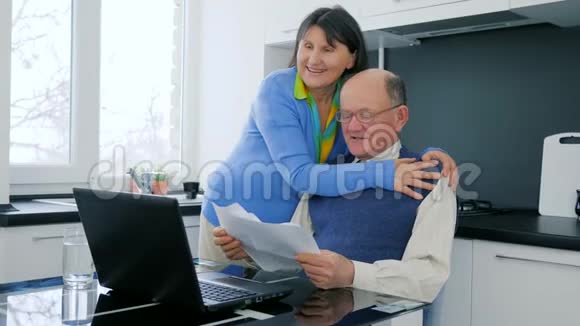网上购物快乐的老年夫妇用笔记本电脑在线支付享受商业上的成功并拥抱在视频的预览图