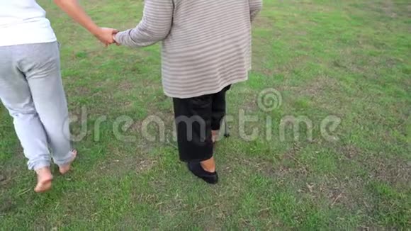 女子慢动作牵着老年妇女的手在公园散步视频的预览图