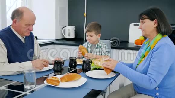 养老金领取者孩子在厨房里和祖父和祖母一起吃面包店产品视频的预览图